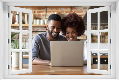 A man and woman are sitting at a table looking at a laptop