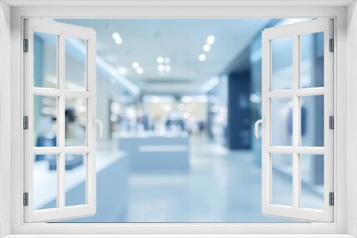 A blurred interior of a modern retail store showcasing clothing displays.