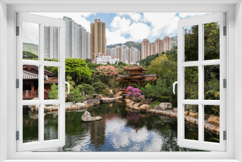 Fototapeta Naklejka Na Ścianę Okno 3D - Traditional wooden teahouse and bridge by the pond at the Nan Lian Garden in Hong Kong, China. High-rise apartment buildings in the background.