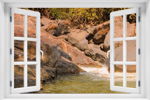 Fototapeta Naklejka Na Ścianę Okno 3D - Beautiful small river with big stones on the coast and a red clay bottom in the tropical jungle of India