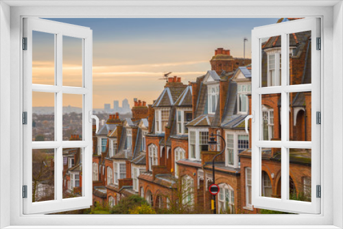 Fototapeta Naklejka Na Ścianę Okno 3D - Typical British brick houses on a cloudy morning with sunrise and Canary Wharf at the background. Panoramic shot from Muswell Hill, London, UK